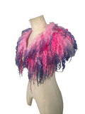 Enhance your wardrobe with our Curly Caplet Statement Wool Collar. Crafted from natural wool and dyed in pink and purple, this striking fashion piece showcases curly locks from Teeswater sheep, skilfully wet and needle felted for a bold appearance. Stand out from the crowd with this exceptional accessory.