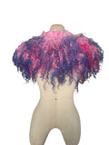 Enhance your wardrobe with our Curly Caplet Statement Wool Collar. Crafted from natural wool and dyed in pink and purple, this striking fashion piece showcases curly locks from Teeswater sheep, skilfully wet and needle felted for a bold appearance. Stand out from the crowd with this exceptional accessory.