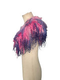 Enhance your wardrobe with our Curly Caplet Statement Wool Collar. Crafted from natural wool and dyed in pink and purple, this striking fashion piece showcases curly locks from Teeswater sheep, skilfully wet and needle felted for a bold appearance. Stand out from the crowd with this exceptional accessory.